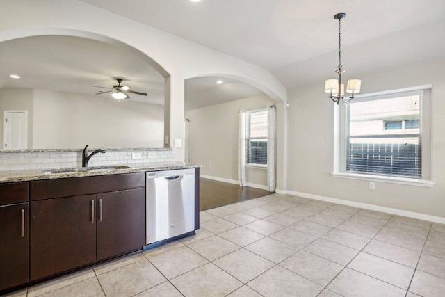 kitchen with a sink, stainless steel dishwasher, decorative backsplash, light stone countertops, and dark brown cabinets