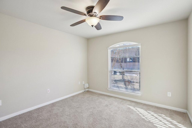 empty room featuring baseboards, light carpet, and a ceiling fan