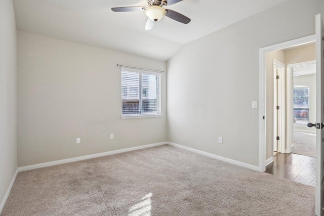 carpeted spare room with baseboards, ceiling fan, and vaulted ceiling