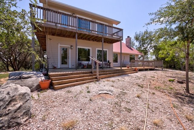 back of property featuring a chimney and a wooden deck