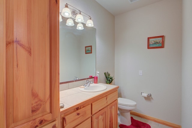 bathroom with vanity, toilet, visible vents, and baseboards