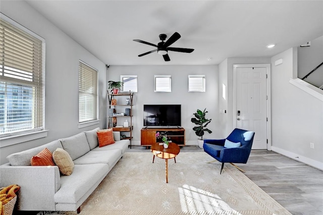 living area featuring wood finished floors, baseboards, a wealth of natural light, and ceiling fan