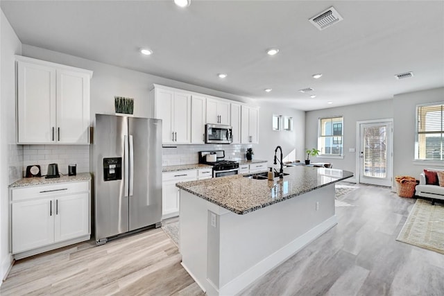 kitchen with a sink, visible vents, appliances with stainless steel finishes, and white cabinetry