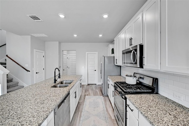 kitchen with visible vents, decorative backsplash, stainless steel appliances, white cabinetry, and a sink