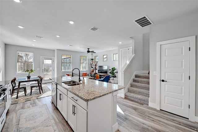 kitchen featuring a sink, visible vents, dishwasher, and white cabinets