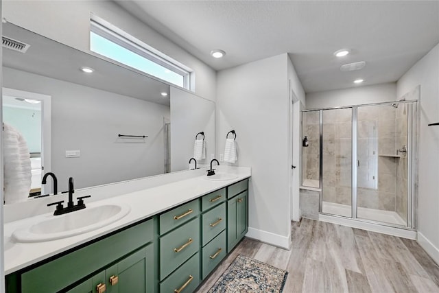 bathroom with a shower stall, wood finished floors, visible vents, and a sink