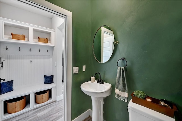 half bath with toilet, wood finished floors, and baseboards