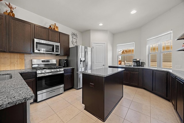 kitchen featuring light stone counters, dark brown cabinetry, appliances with stainless steel finishes, and light tile patterned flooring