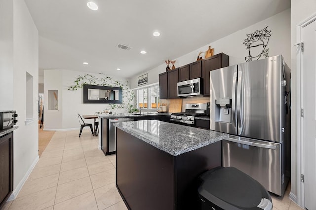 kitchen with visible vents, a kitchen island, stainless steel appliances, light tile patterned floors, and dark brown cabinets