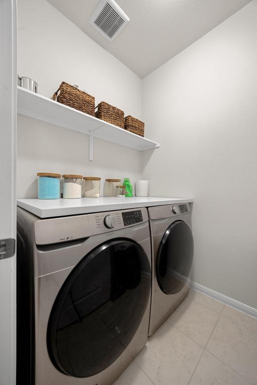 laundry room with visible vents, baseboards, laundry area, light tile patterned flooring, and washer and dryer