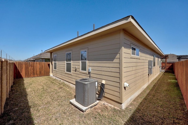 view of property exterior with central air condition unit, a yard, and a fenced backyard