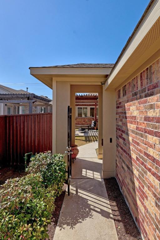 view of exterior entry featuring brick siding and fence