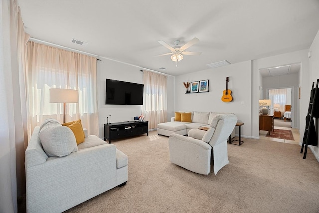 carpeted living room with visible vents, attic access, and ceiling fan