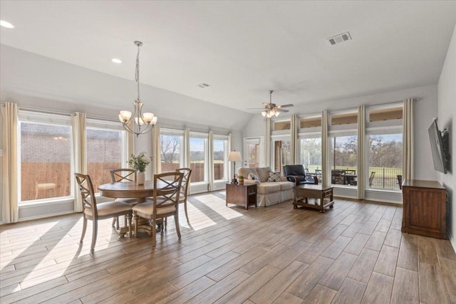 dining space with wood finished floors, visible vents, recessed lighting, vaulted ceiling, and ceiling fan with notable chandelier