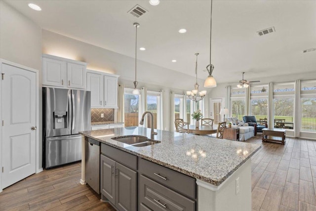 kitchen featuring visible vents, light wood-type flooring, a sink, appliances with stainless steel finishes, and decorative backsplash