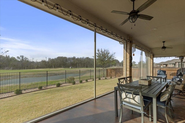 sunroom featuring a ceiling fan and a water view