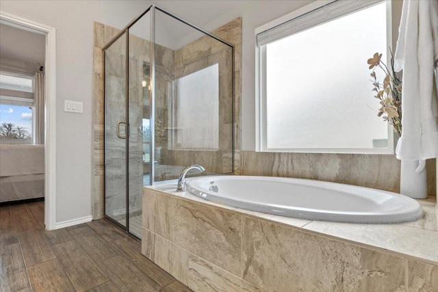 ensuite bathroom with connected bathroom, a shower stall, a garden tub, and wood finished floors