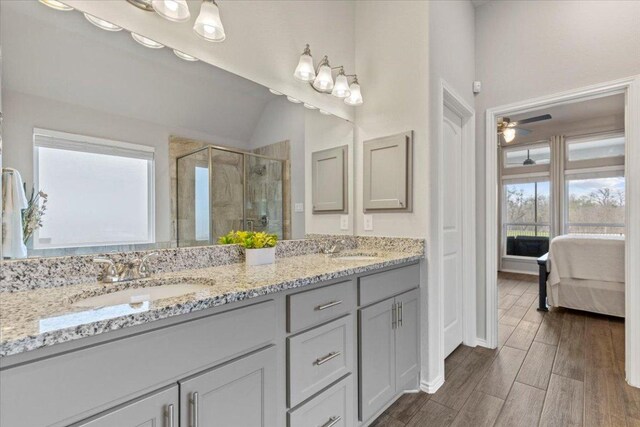 ensuite bathroom with wood finish floors, a sink, connected bathroom, a shower stall, and double vanity