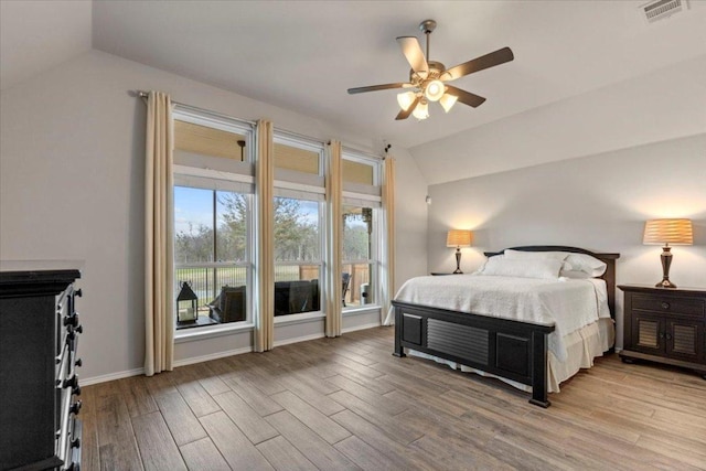 bedroom with lofted ceiling, wood finished floors, visible vents, and baseboards