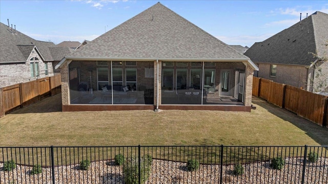 back of property with a yard, a fenced backyard, brick siding, and a sunroom