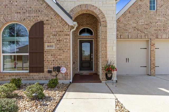 entrance to property with a garage, brick siding, and concrete driveway