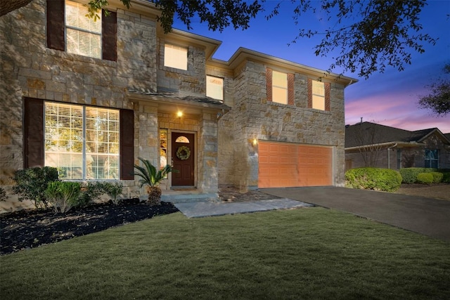 view of front of home featuring aphalt driveway, an attached garage, stone siding, and a front lawn