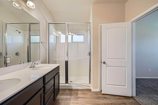 bathroom featuring a sink, a stall shower, wood finished floors, and double vanity