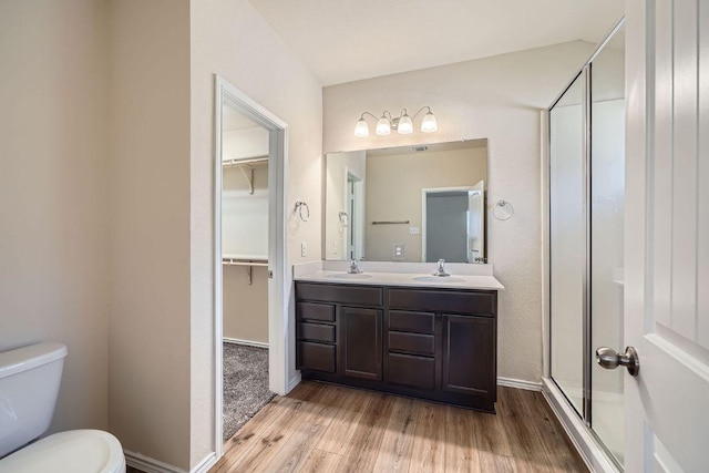 bathroom with wood finished floors, a shower stall, toilet, and a sink