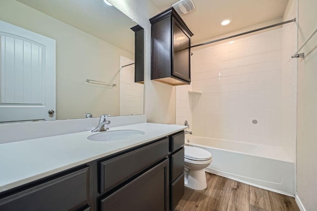 bathroom featuring visible vents, tub / shower combination, toilet, wood finished floors, and vanity