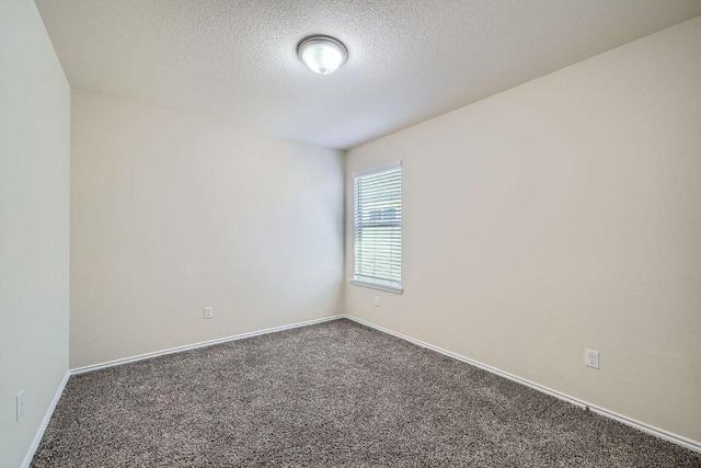 spare room featuring baseboards, carpet, and a textured ceiling