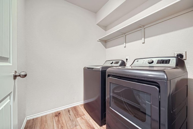 laundry area with laundry area, light wood-style floors, baseboards, and washer and clothes dryer