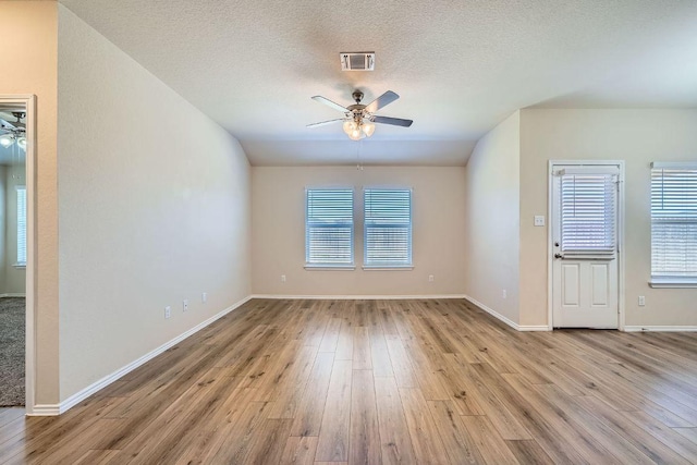 unfurnished room with ceiling fan, visible vents, a textured ceiling, and wood finished floors