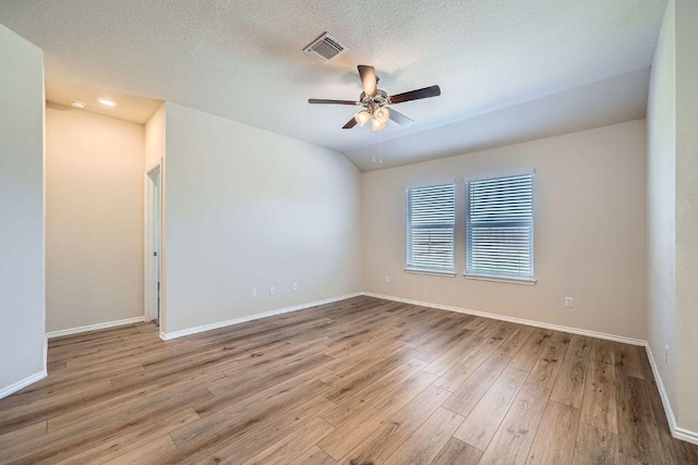 empty room featuring wood finished floors, baseboards, visible vents, lofted ceiling, and ceiling fan