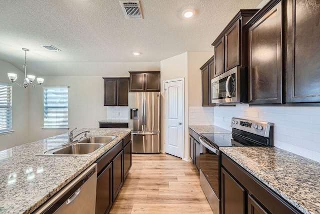 kitchen featuring visible vents, a sink, stainless steel appliances, light wood-style floors, and dark brown cabinetry