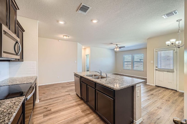 kitchen featuring light wood finished floors, visible vents, stainless steel appliances, and a sink