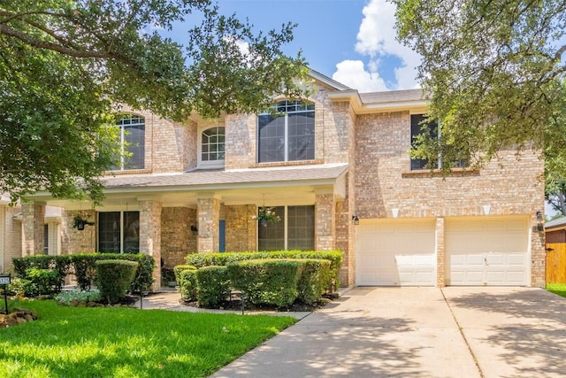 traditional-style home featuring brick siding, an attached garage, driveway, and a front yard