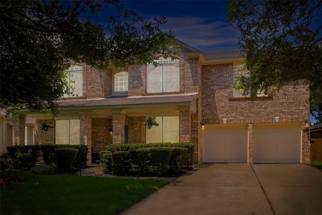 traditional-style house featuring concrete driveway, brick siding, and a garage