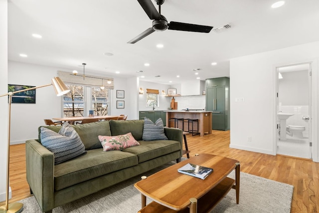 living room with ceiling fan with notable chandelier, light wood-style flooring, recessed lighting, and visible vents