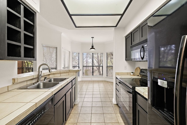 kitchen featuring black appliances, ornamental molding, a sink, tile countertops, and light tile patterned floors