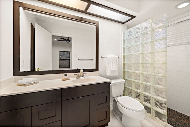 bathroom featuring vanity, toilet, a walk in shower, and ceiling fan