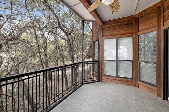 unfurnished sunroom featuring beam ceiling and ceiling fan