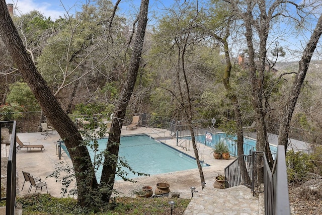 community pool with fence and a patio area