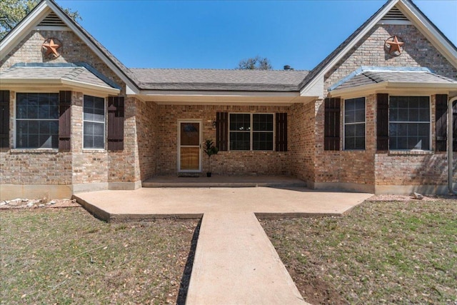 view of front of property with a front lawn, brick siding, and a patio