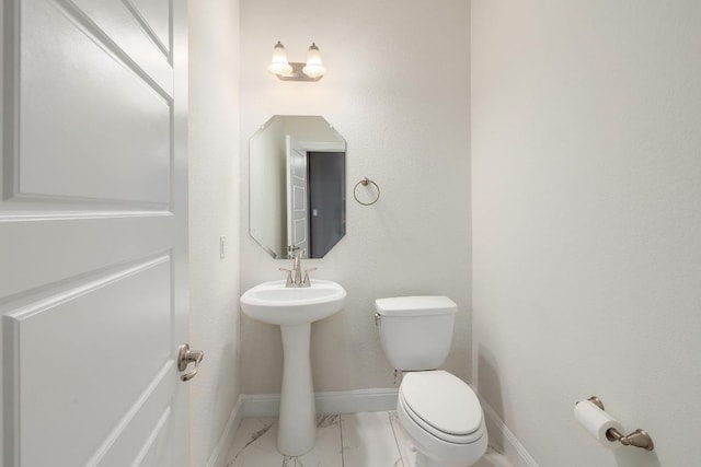 bathroom featuring marble finish floor, toilet, and baseboards