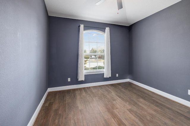 unfurnished room featuring baseboards, dark wood finished floors, and a ceiling fan