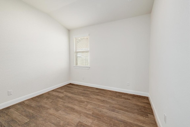 unfurnished room with baseboards, lofted ceiling, and wood finished floors