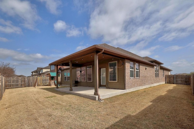 rear view of house featuring a patio, a playground, a fenced backyard, and brick siding