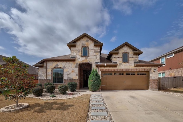 view of front of house featuring fence, brick siding, stone siding, and driveway