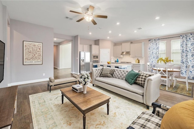 living room featuring visible vents, a ceiling fan, recessed lighting, light wood-style floors, and baseboards