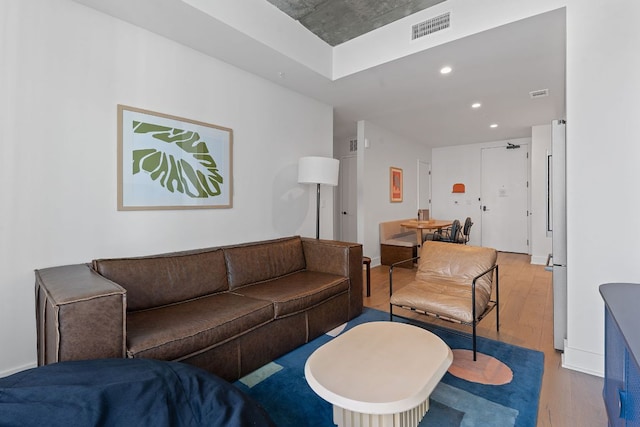 living room with recessed lighting, wood finished floors, visible vents, and baseboards